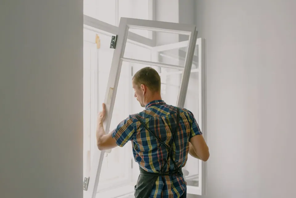 Installer lifting a new window sash into its opening